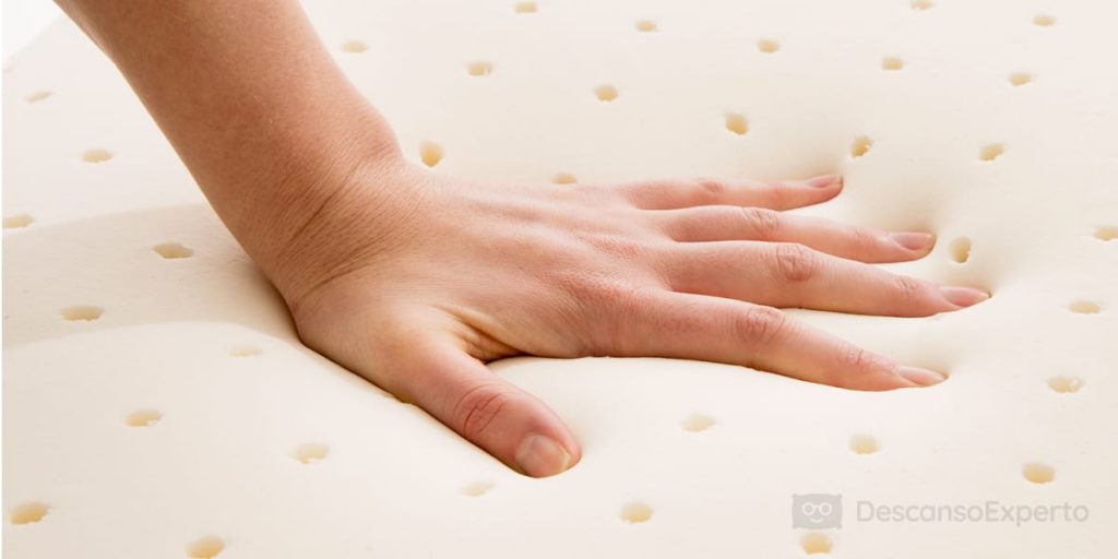 Mano sobre la superficie de un colchón de látex